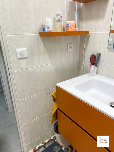 Etagères oranges accordées avec le meuble de salle de bain et le carrelage au sol